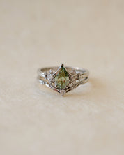 Silver ring with a green gemstone on a beige background