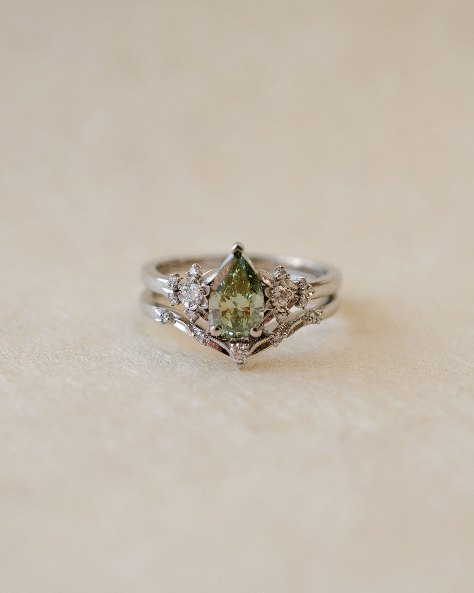Silver ring with a green gemstone on a beige background