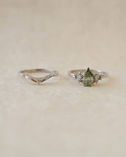 platinum V shaped wedding band next to green diamond engagement ring