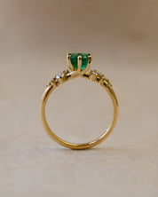 Gold ring with a green gemstone on a beige background