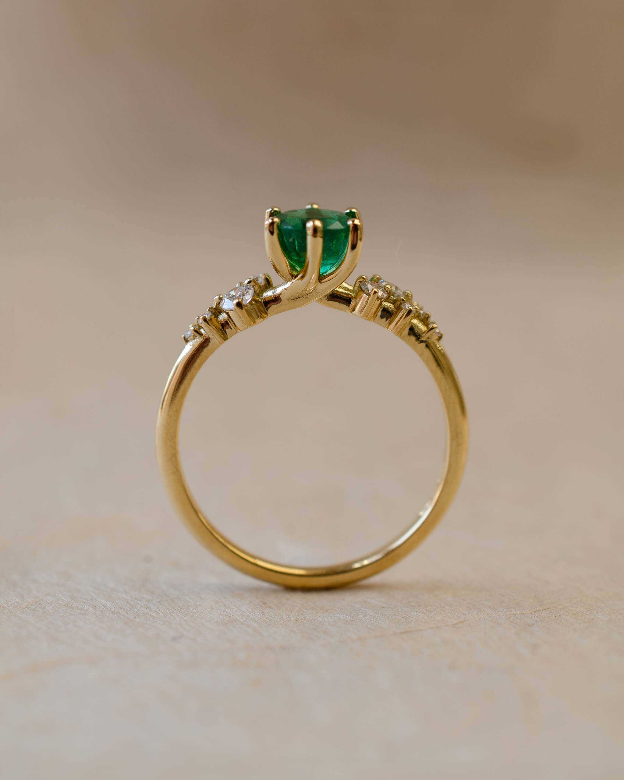 Gold ring with a green gemstone on a beige background