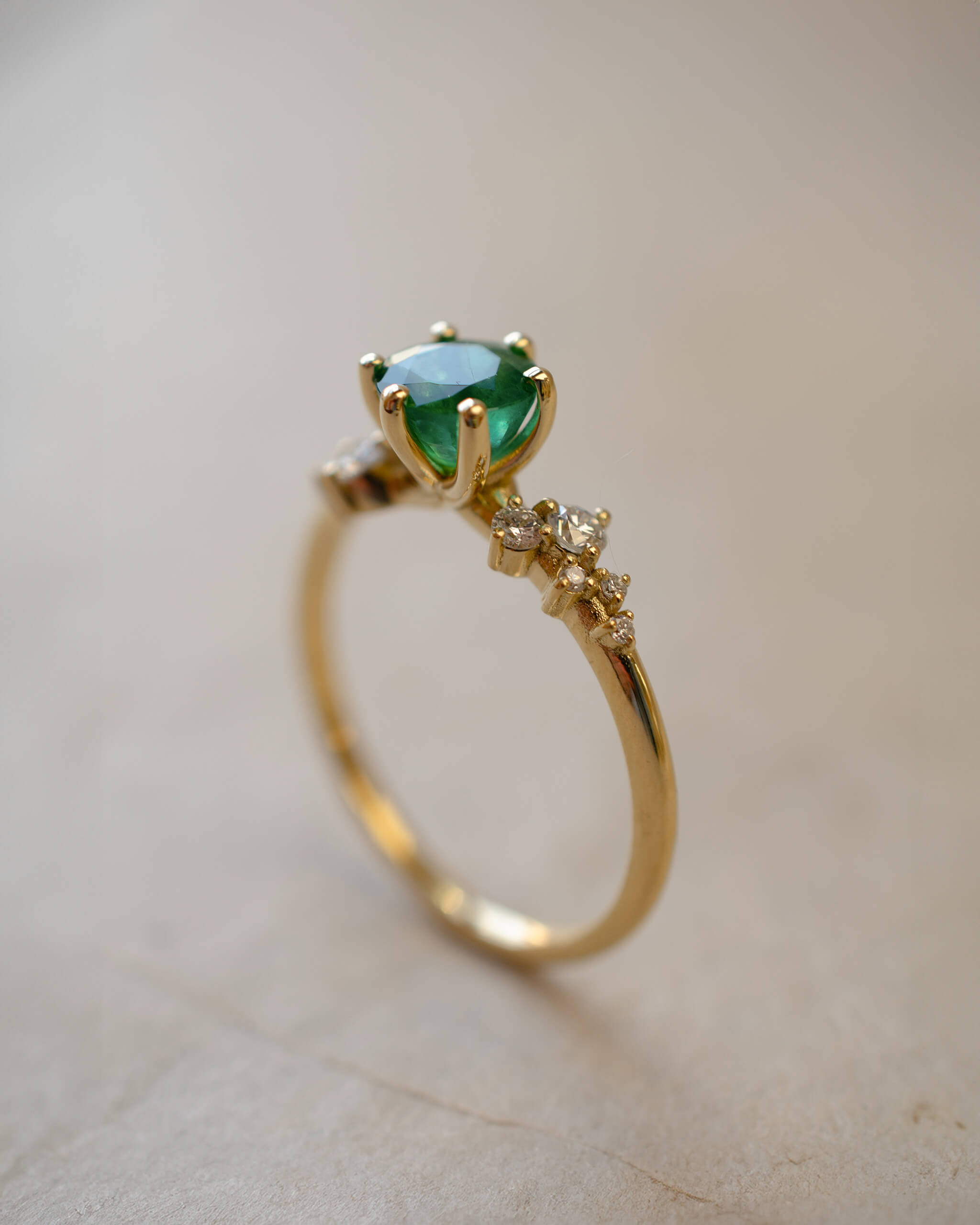 Gold ring with a green gemstone on a light background