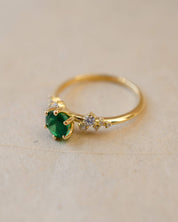 Gold ring with a green gemstone on a beige background