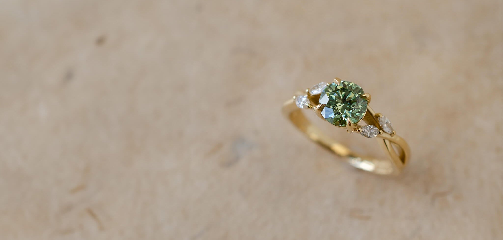 Yellow gold engagement ring with green diamond and marquise leaves