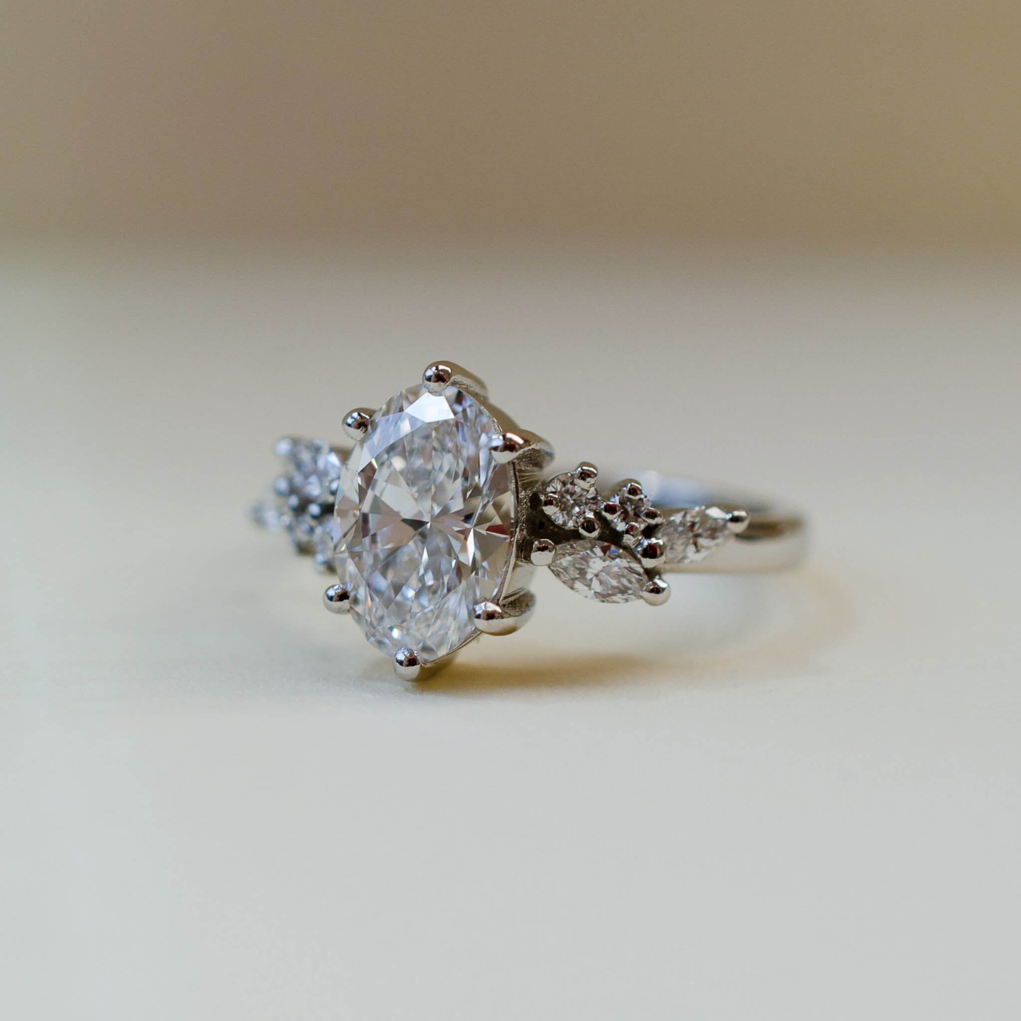 A platinum scatter shoulder style engagement ring with an oval white diamond