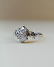 A platinum scatter shoulder style engagement ring with an oval white diamond