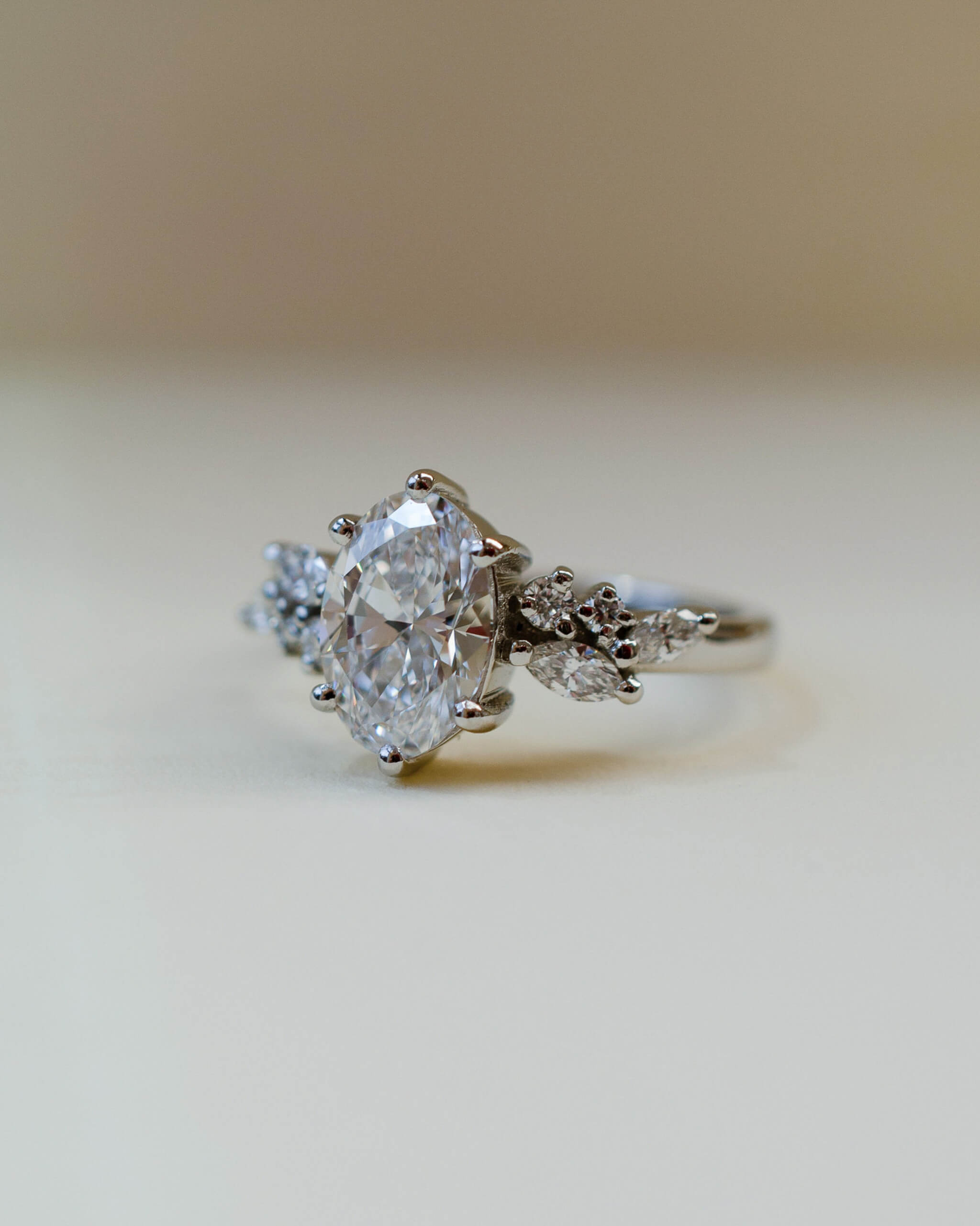 A platinum scatter shoulder style engagement ring with an oval white diamond