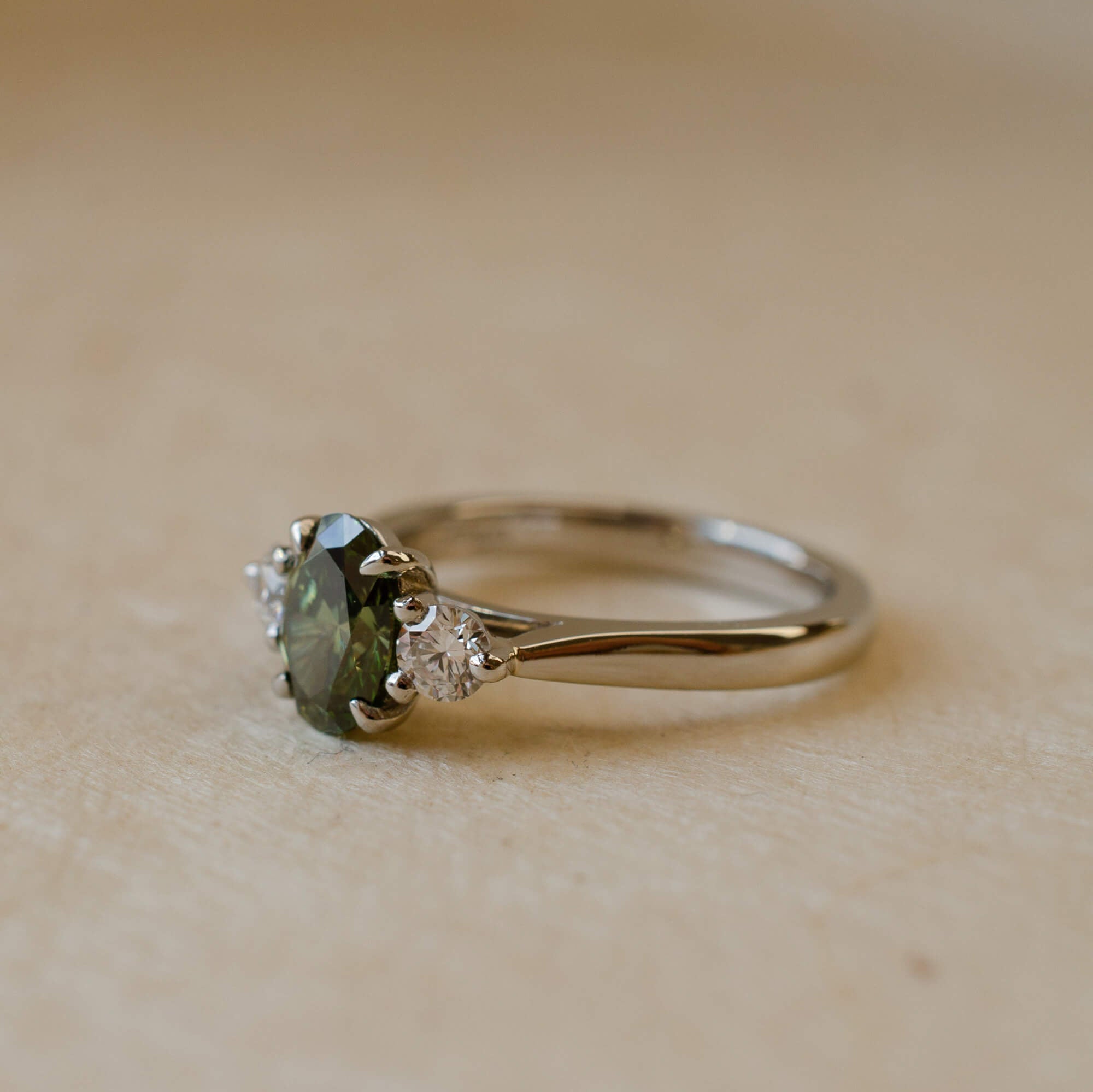 platinum ring with green lab-grown diamond and two white diamonds 
