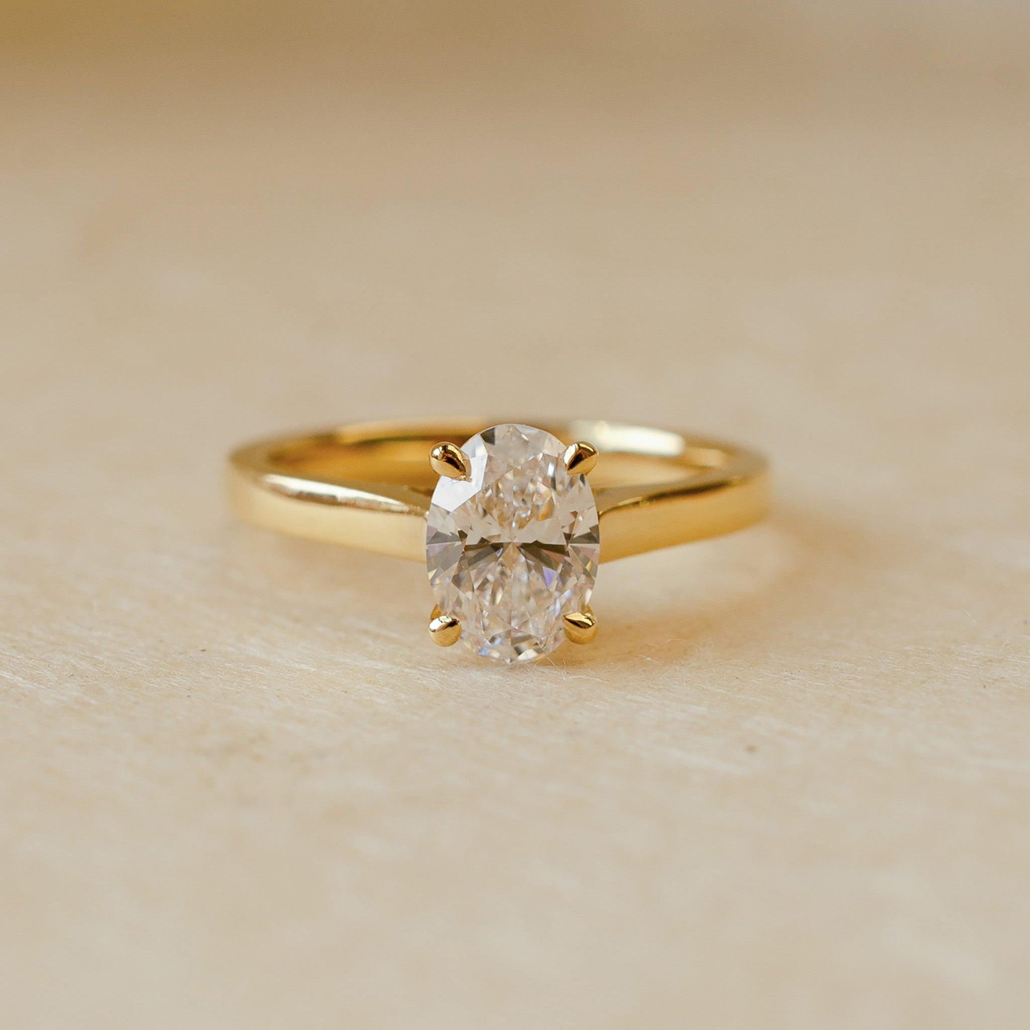 Gold ring with a diamond on a beige background