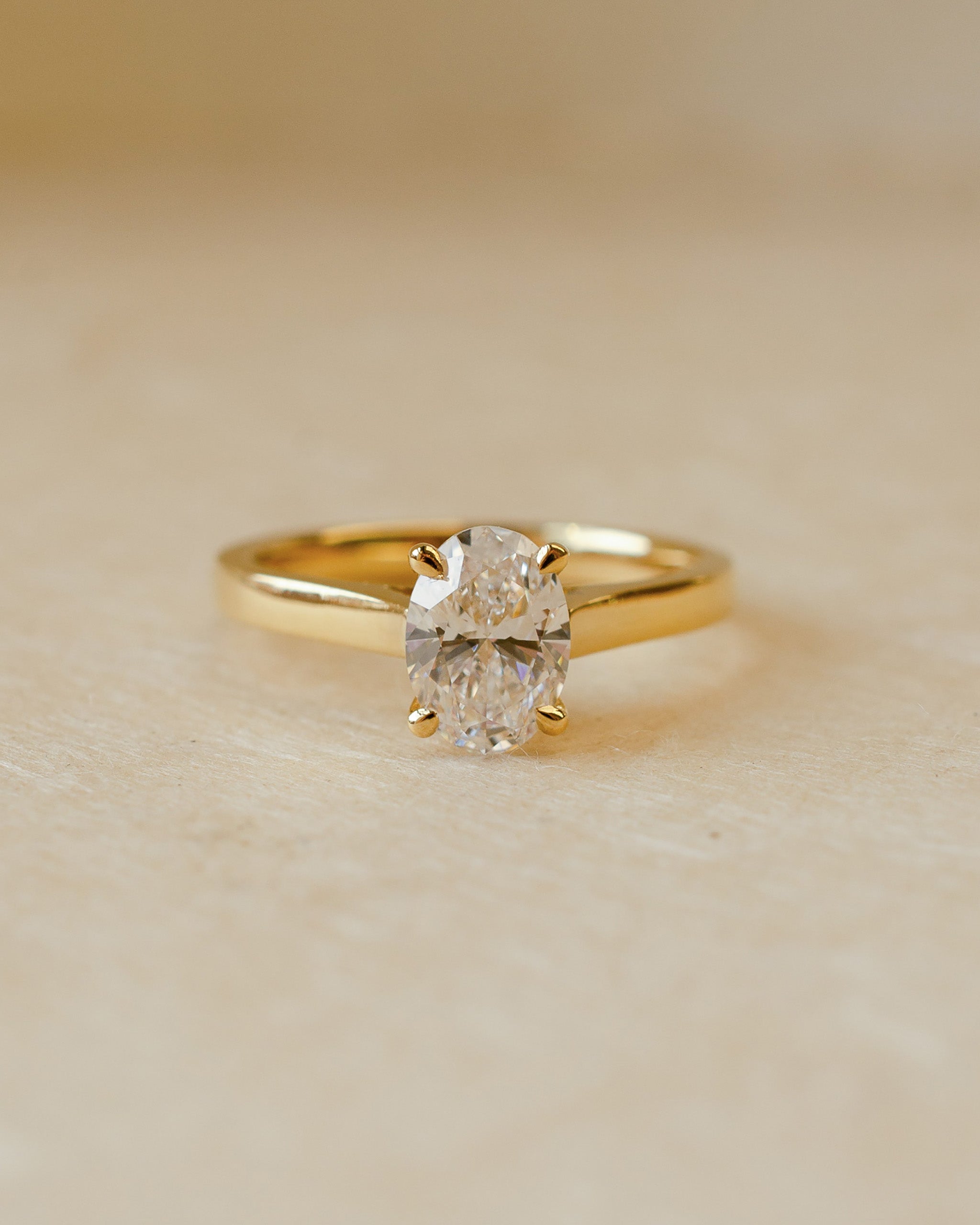 Gold ring with a diamond on a beige background