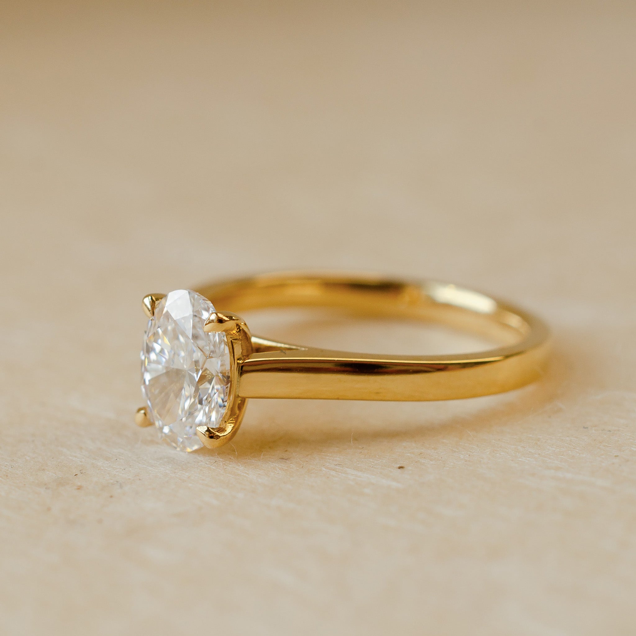 Gold ring with a diamond on a beige background