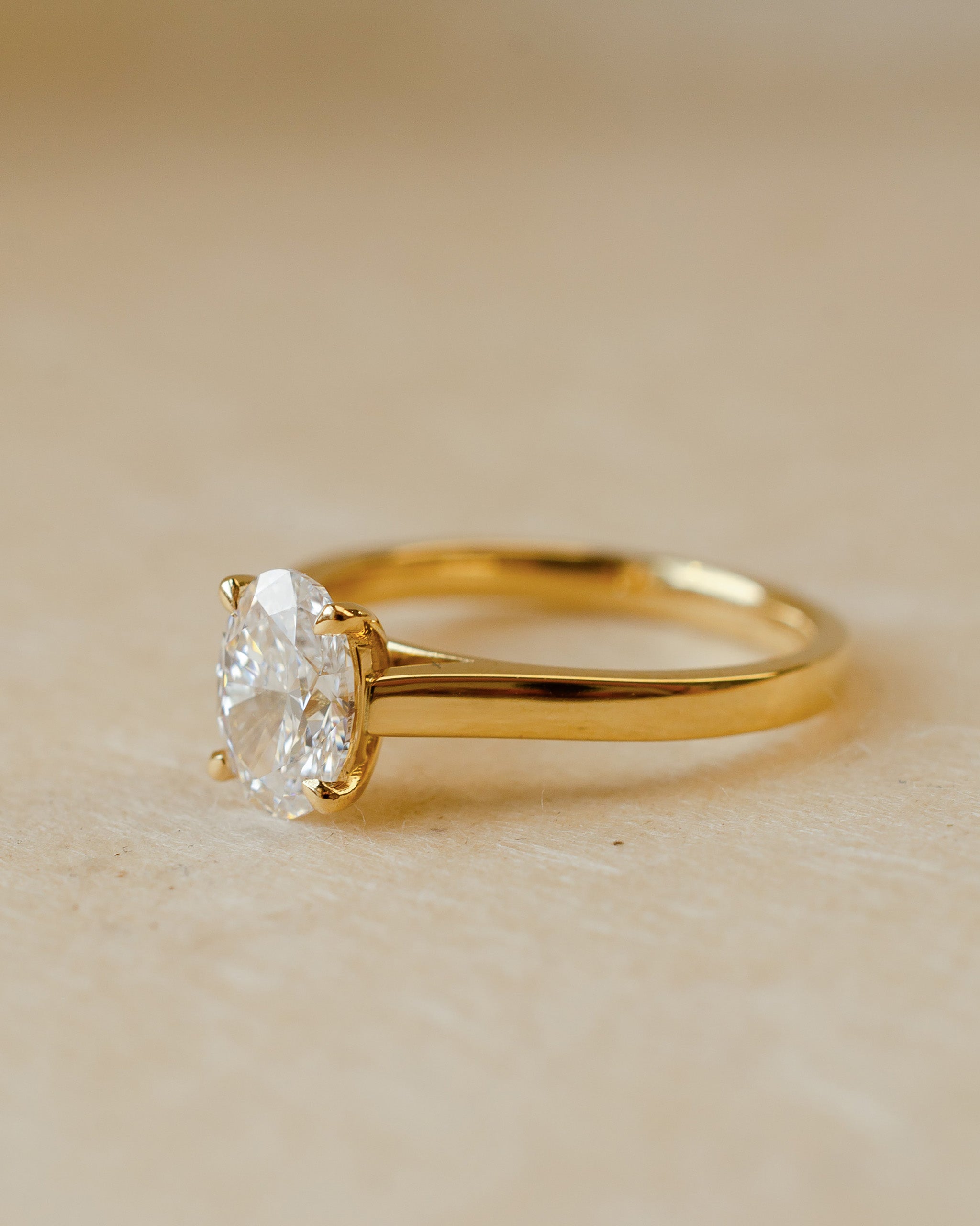 Gold ring with a diamond on a beige background