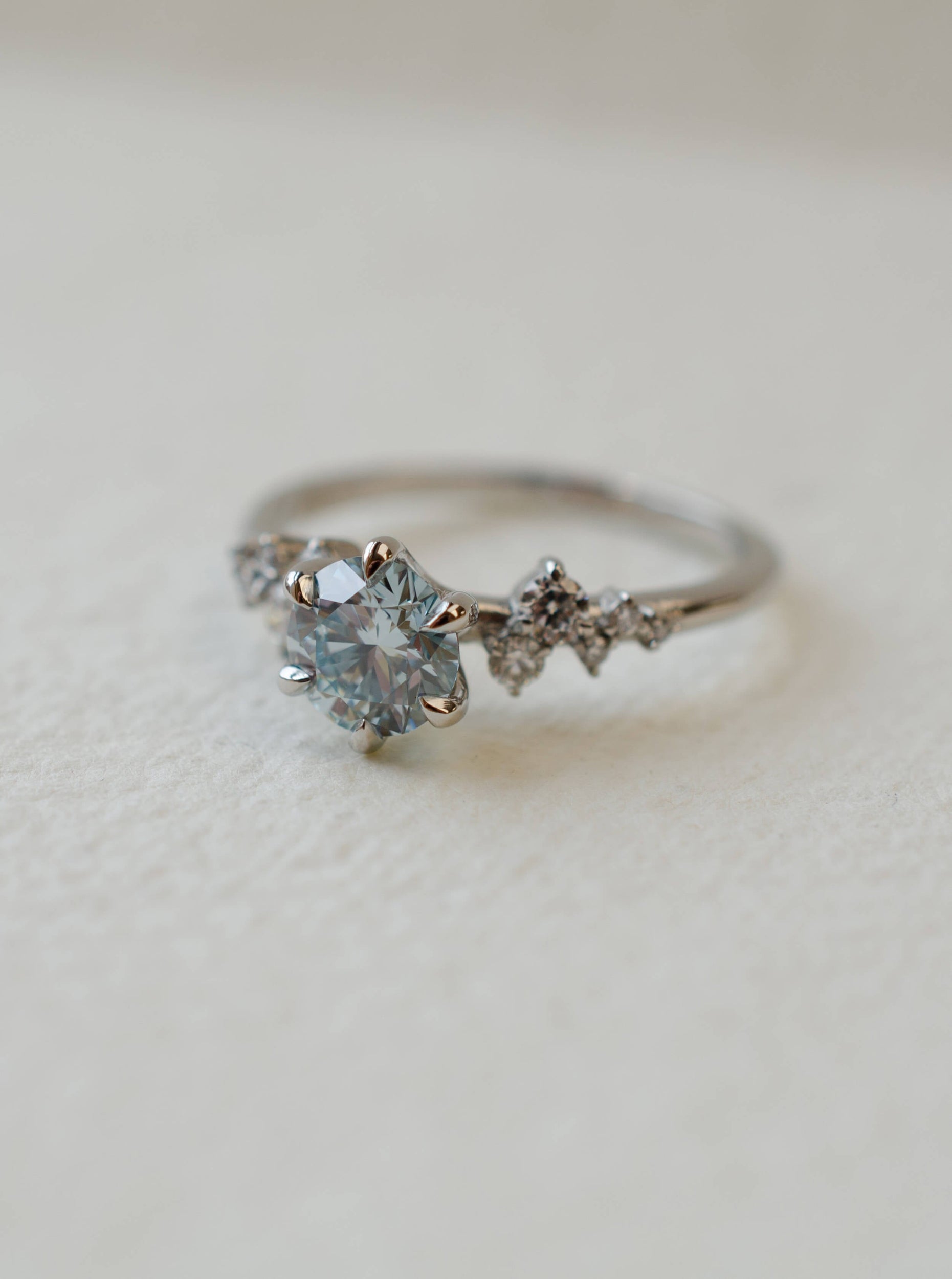 blue diamond delicate engagement ring with scatter set diamond shoulders