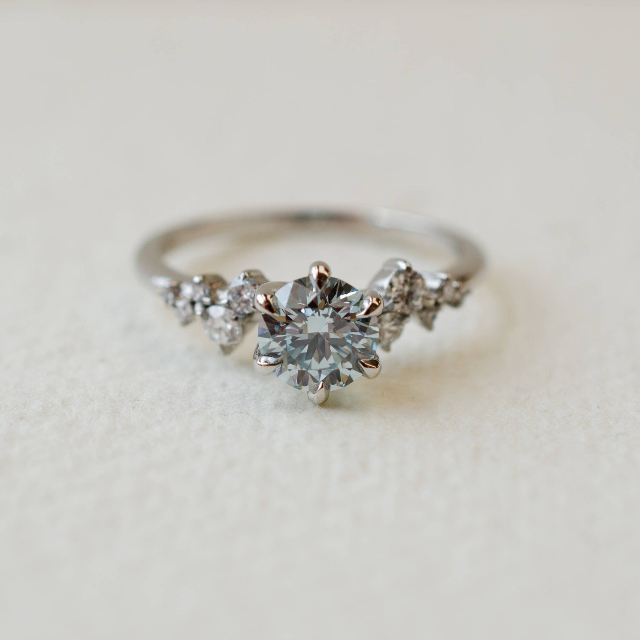 platinum and blue diamond engagement ring with scattered diamond shoulders