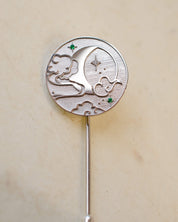 Silver brooch with moon and star design on a beige background