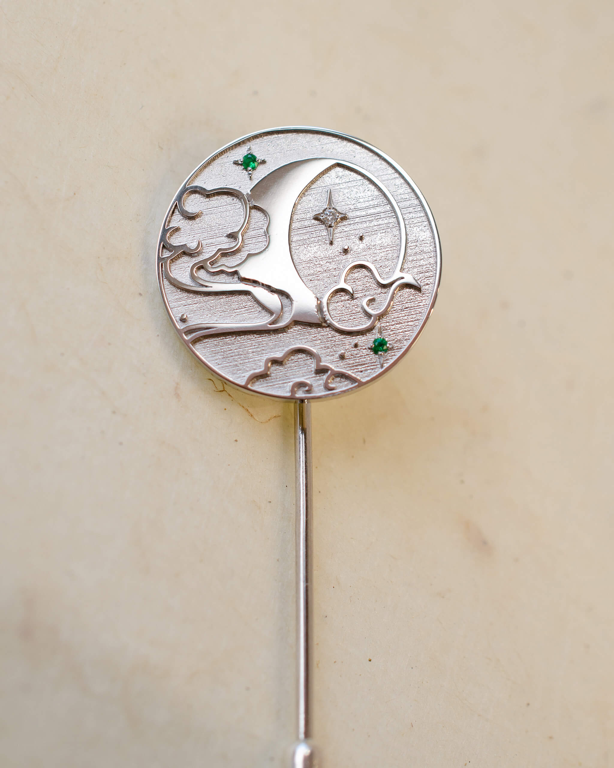 Silver brooch with moon and star design on a beige background