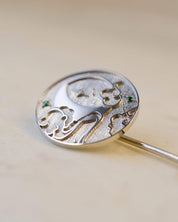 Silver brooch with star and mood design on a beige background