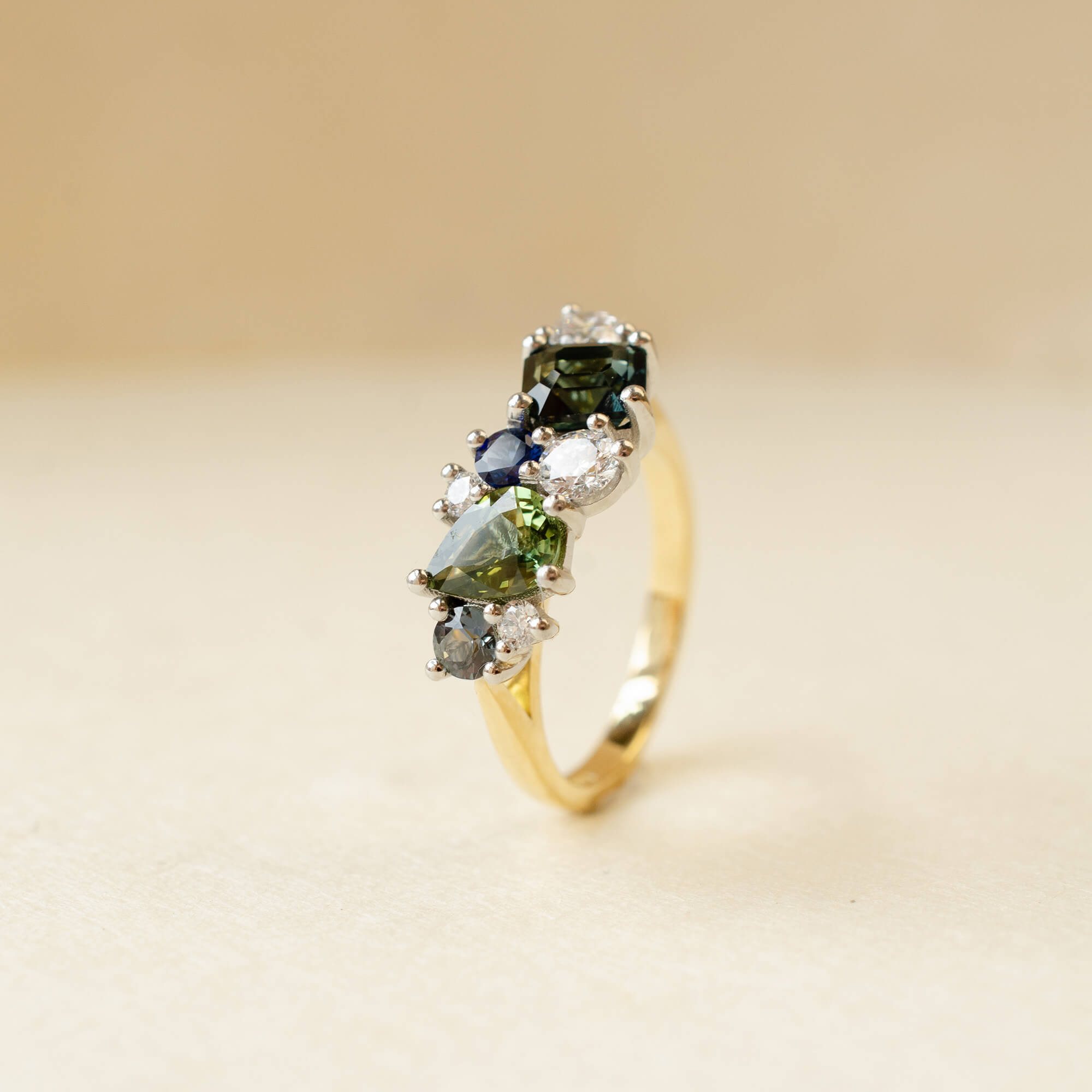 gold ring with diamonds and green, blue and teal sapphires
