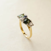 Gold ring with green gemstones on a beige background