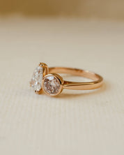 Rose gold ring with two diamonds on a beige background