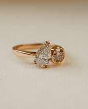 Rose gold ring with two diamonds on a beige background