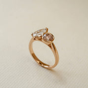 Rose gold ring with two diamonds on a beige background
