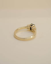 Yellow gold Art Deco style engagement ring set with an emerald cut blue sapphire and baguette cut diamond side stones.