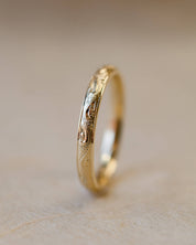 Gold ring with hand engraved design on a beige background