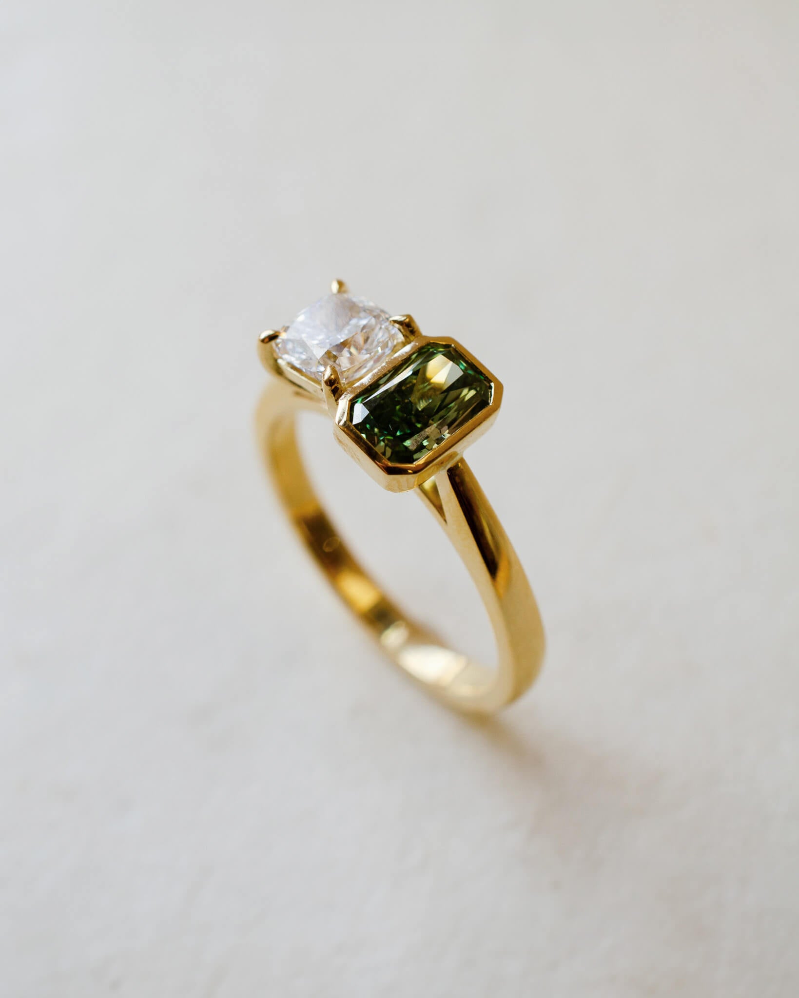 A two stone engagement ring with a white and a green lab-grown diamond