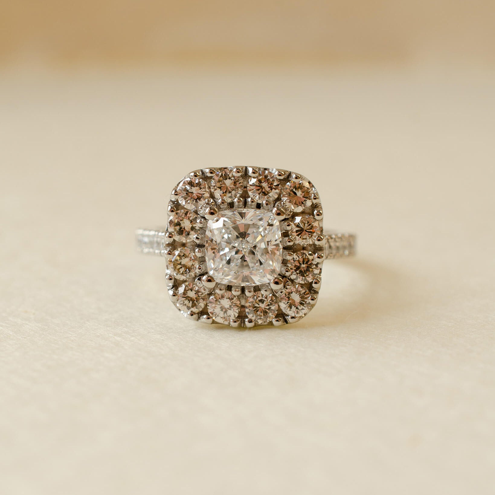 A diamond cluster halo style ring with a cushion cut centre stone