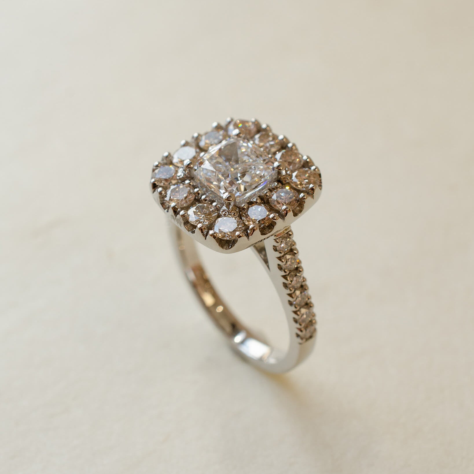 A diamond cluster halo style ring with a cushion cut centre stone