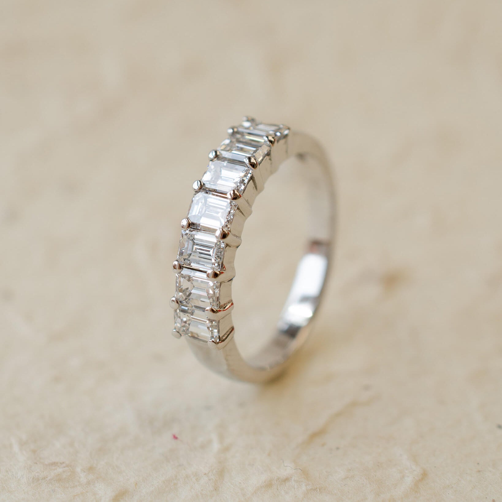 A platinum eternity ring with seven radiant cut white diamonds in claw settings