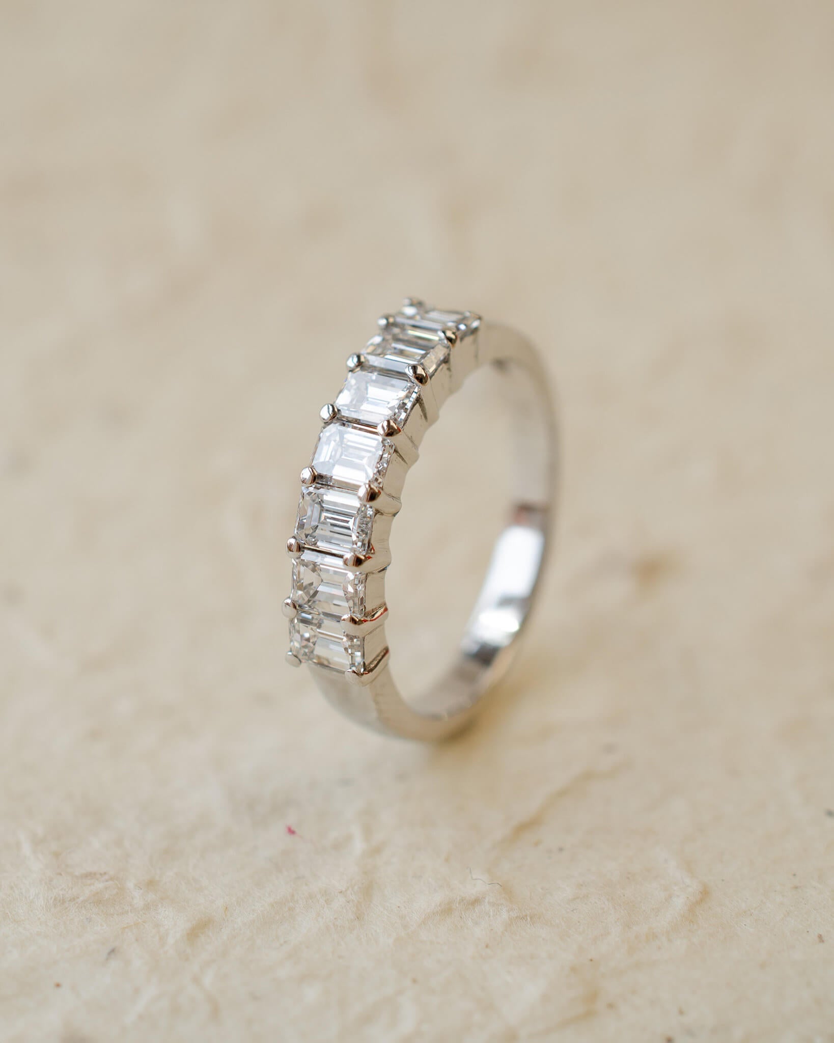 A platinum eternity ring with seven radiant cut white diamonds in claw settings