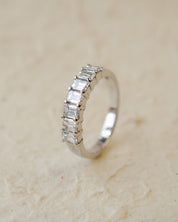 A platinum eternity ring with seven radiant cut white diamonds in claw settings