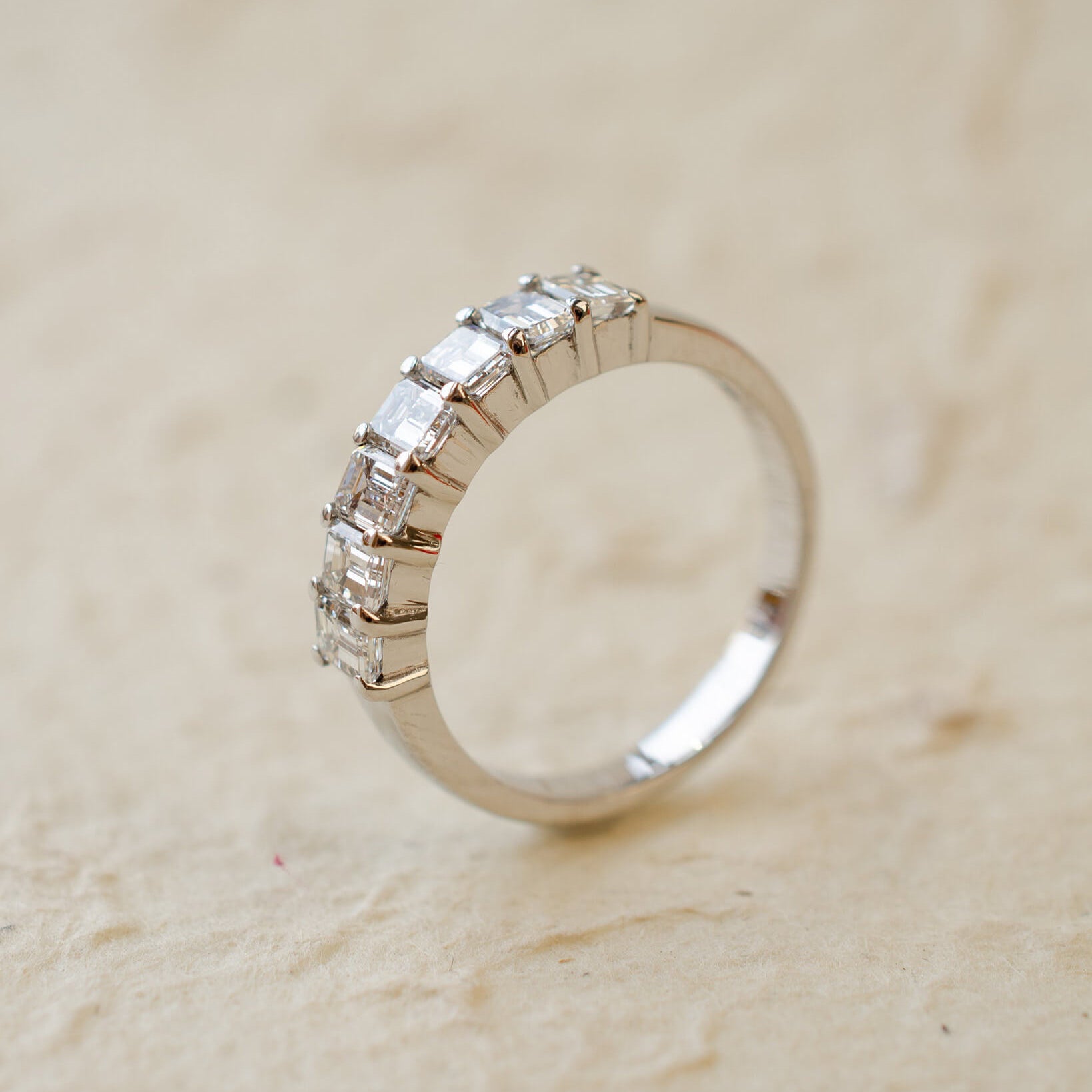 A platinum eternity ring with seven radiant cut white diamonds in claw settings