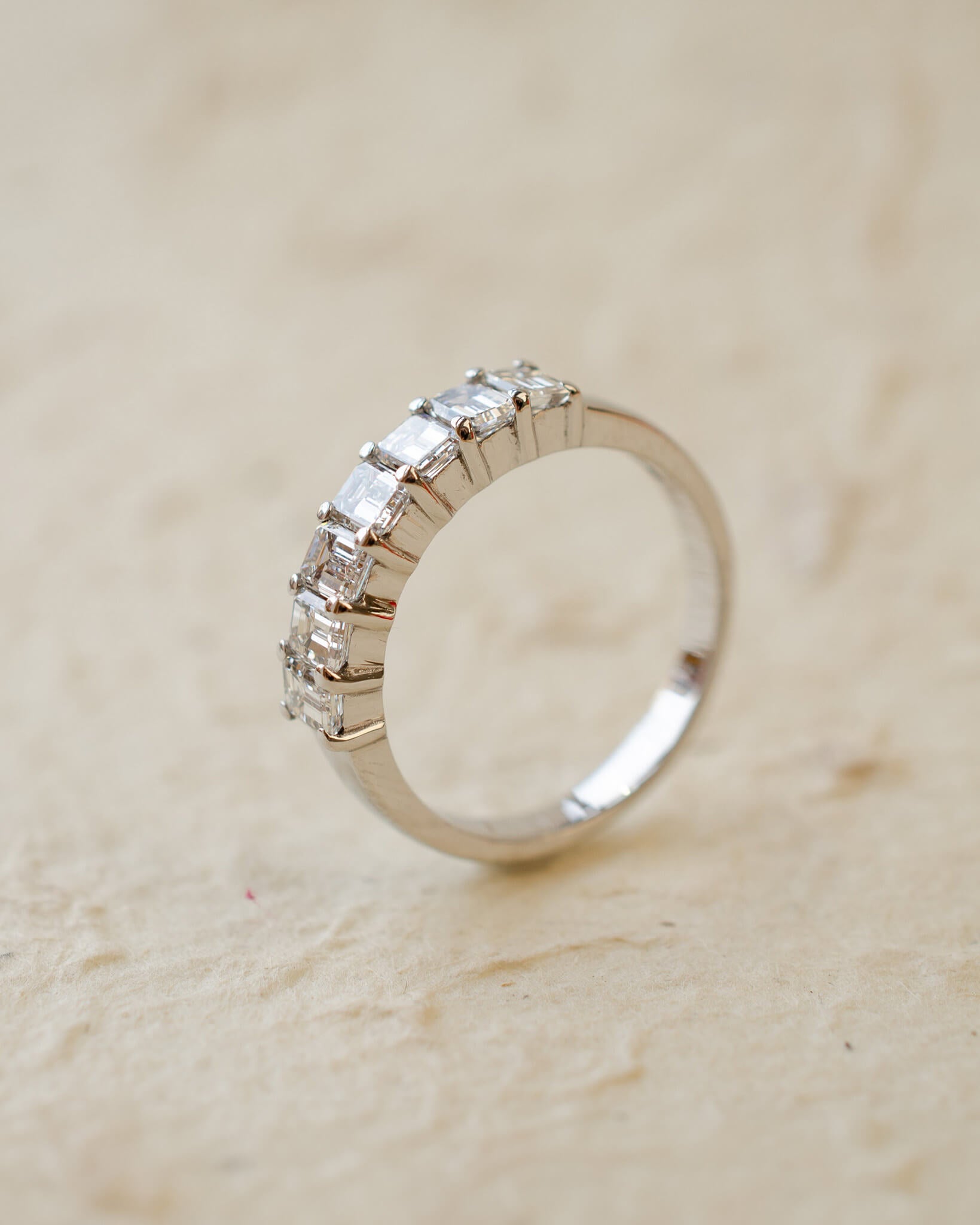 A platinum eternity ring with seven radiant cut white diamonds in claw settings