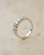 A platinum eternity ring with seven radiant cut white diamonds in claw settings