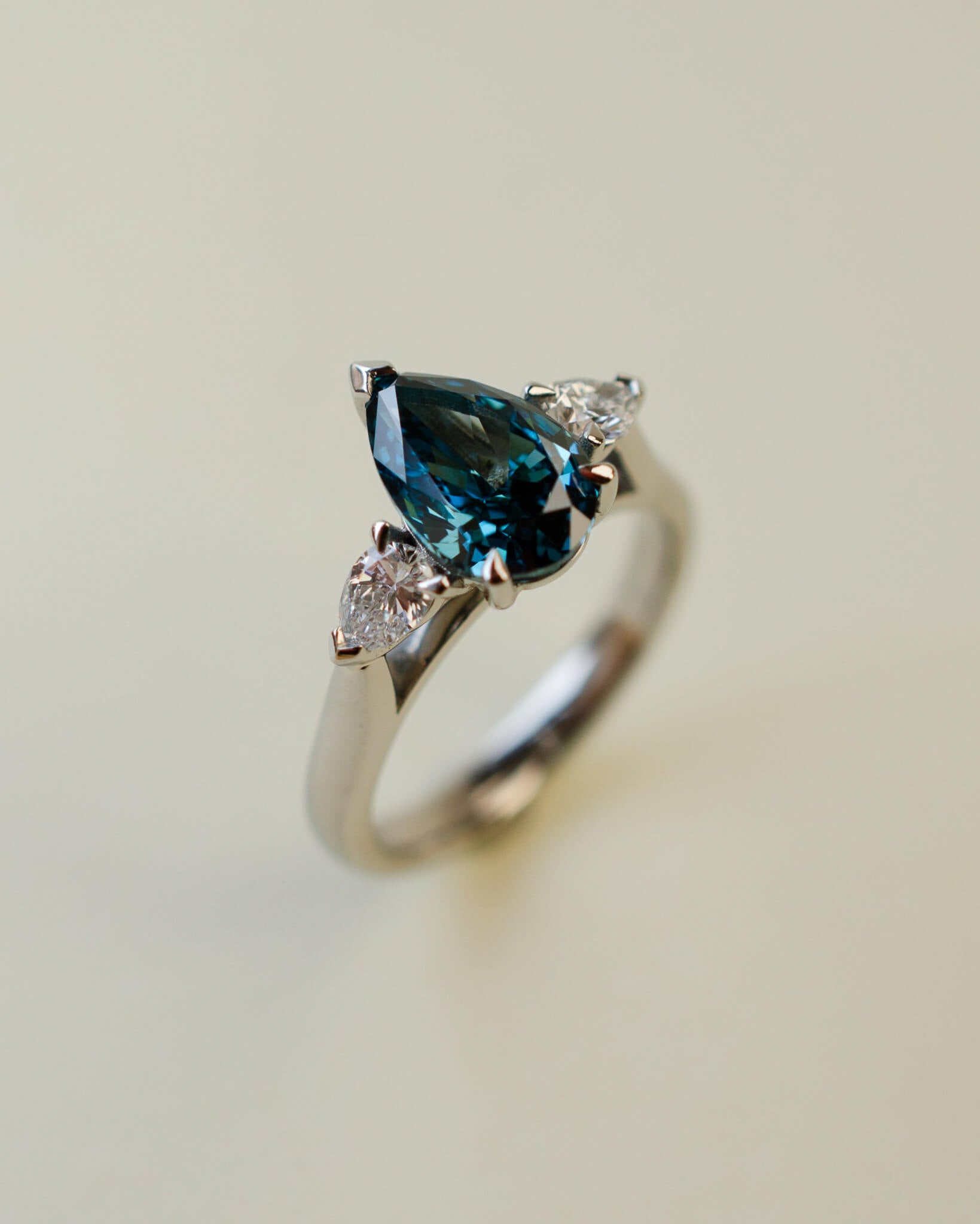 trilogy ring with teal pear cut diamond centre stone and white pear diamond side stones