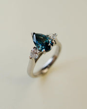 trilogy ring with teal pear cut diamond centre stone and white pear diamond side stones
