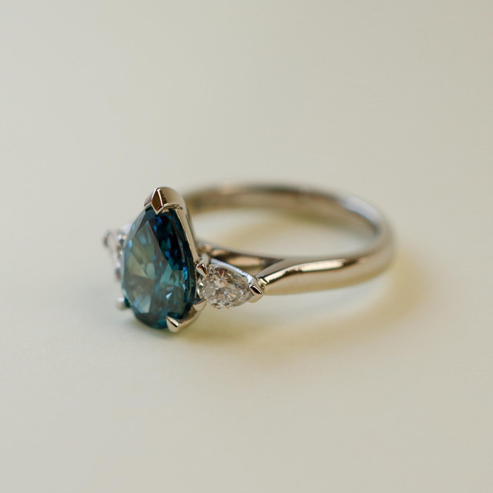 trilogy ring with teal pear cut diamond centre stone and white pear diamond side stones