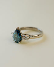trilogy ring with teal pear cut diamond centre stone and white pear diamond side stones